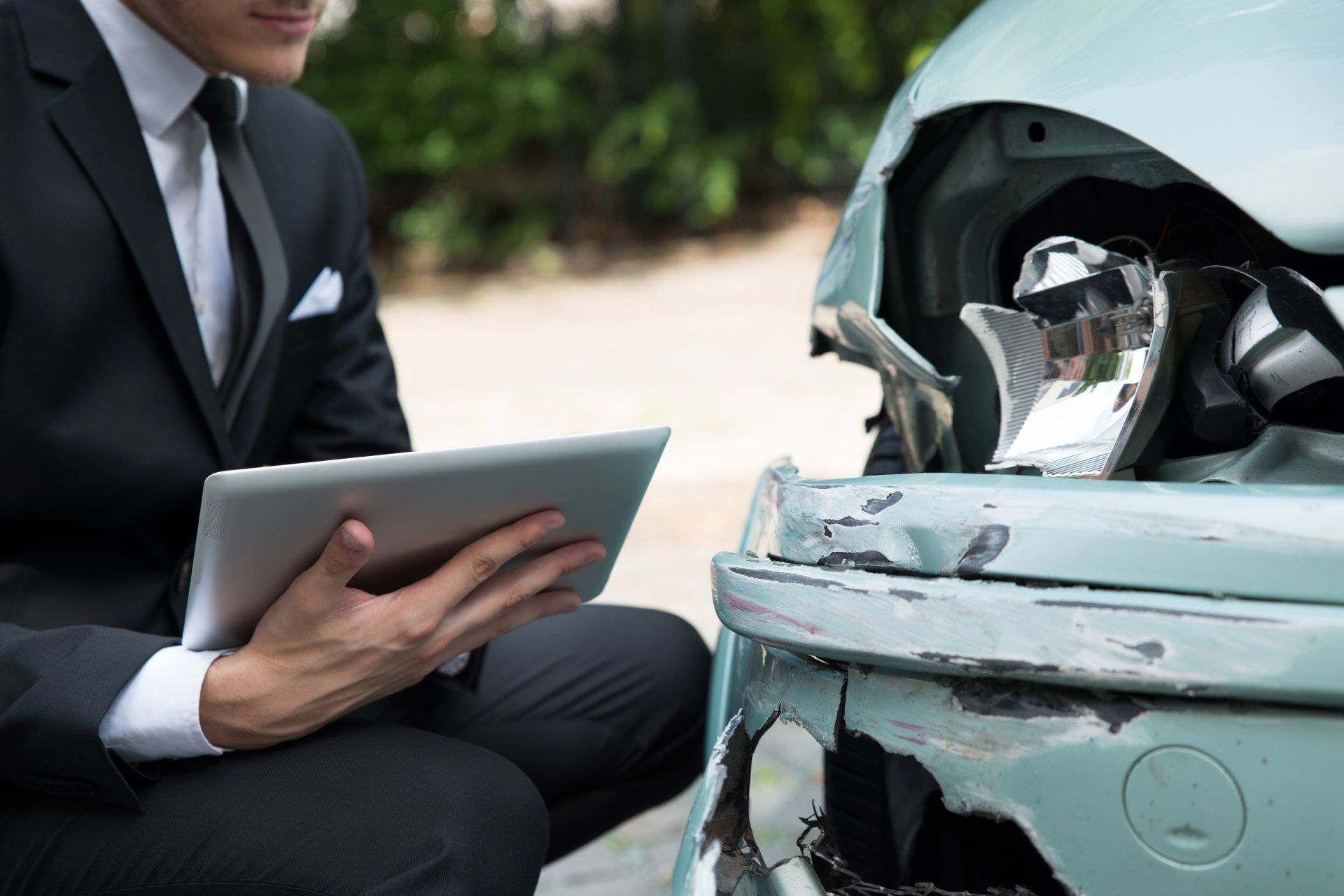 Man with tablet looking at damaged car Man with tablet looking at damaged car