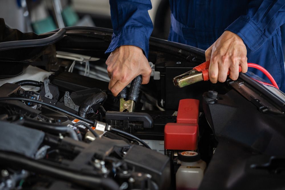 A Man Is Charging A Car Battery With A Jump Starter — Bernie's Tyres In Kawana, QLD