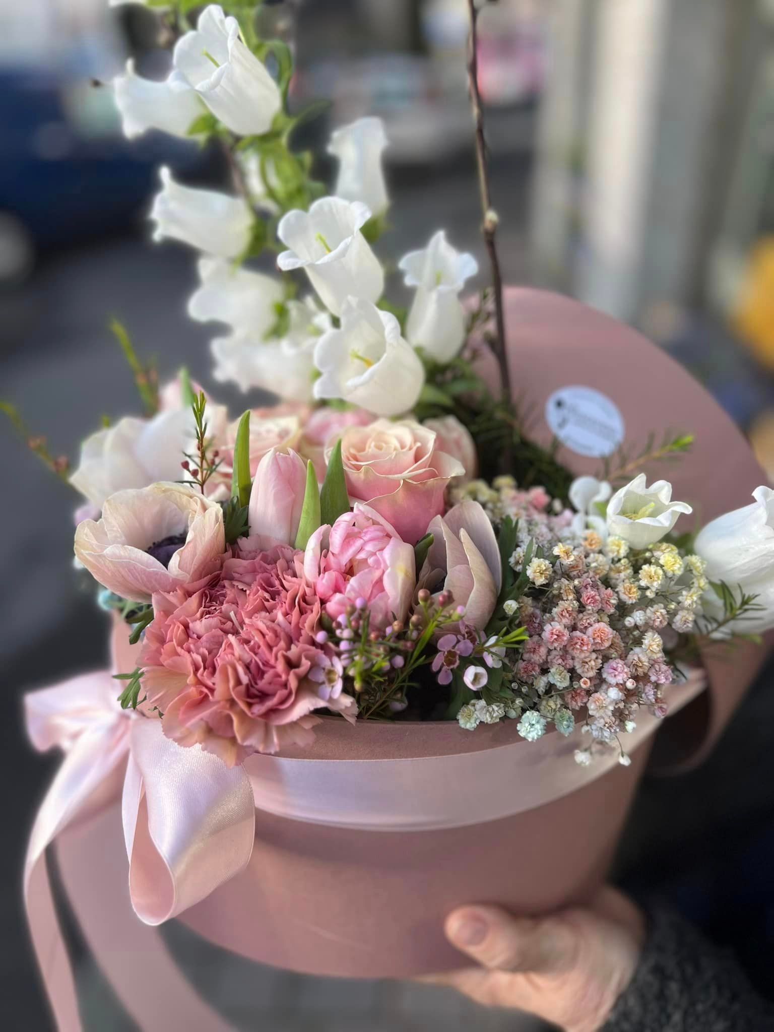 Una persona tiene in mano una scatola rosa piena di fiori.