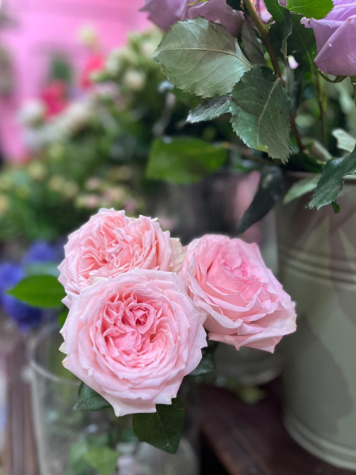 Un primo piano di tre rose rosa in un vaso su un tavolo.