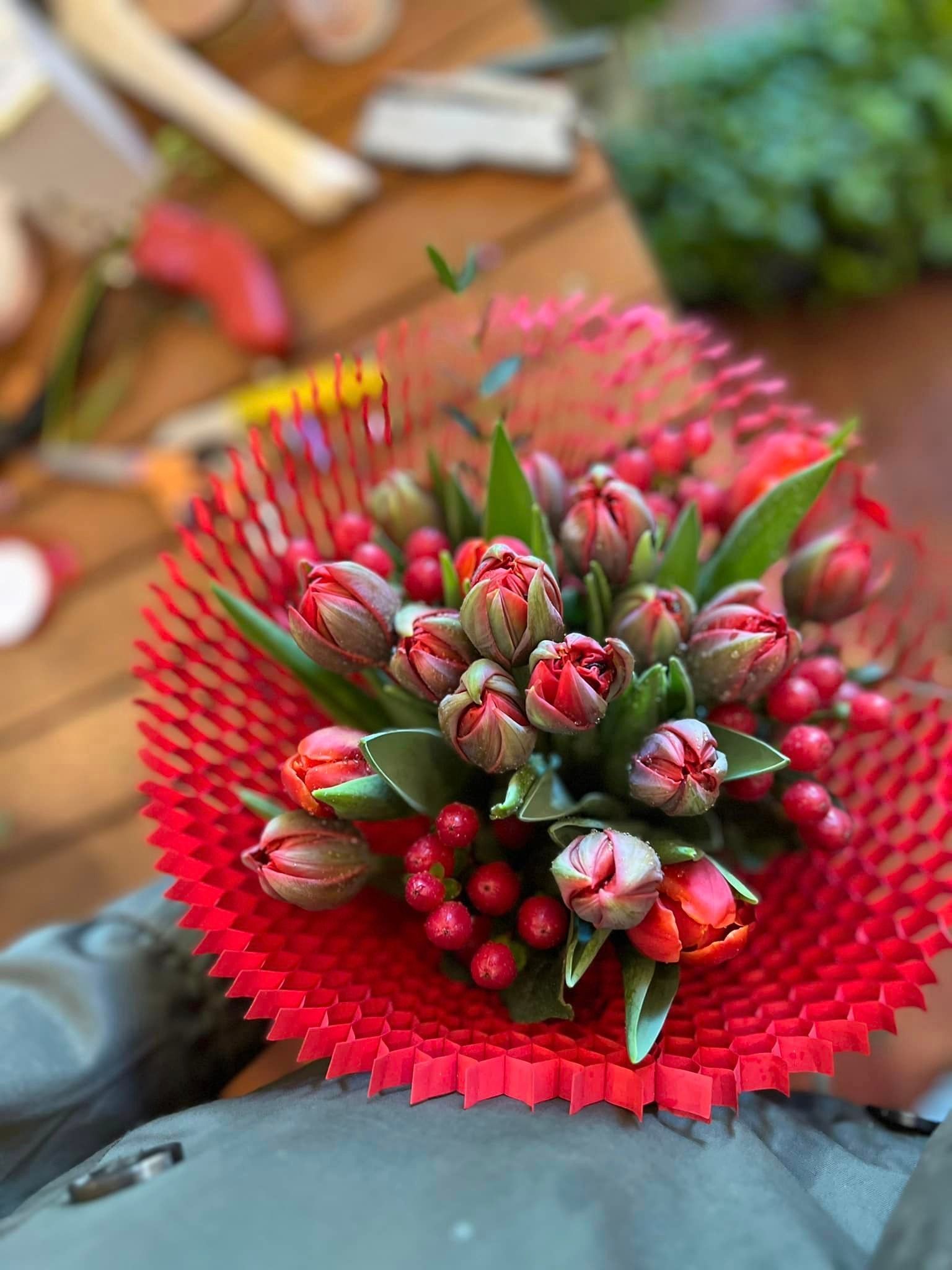Un mazzo di fiori e bacche rossi è avvolto in un sacchetto di plastica rossa.