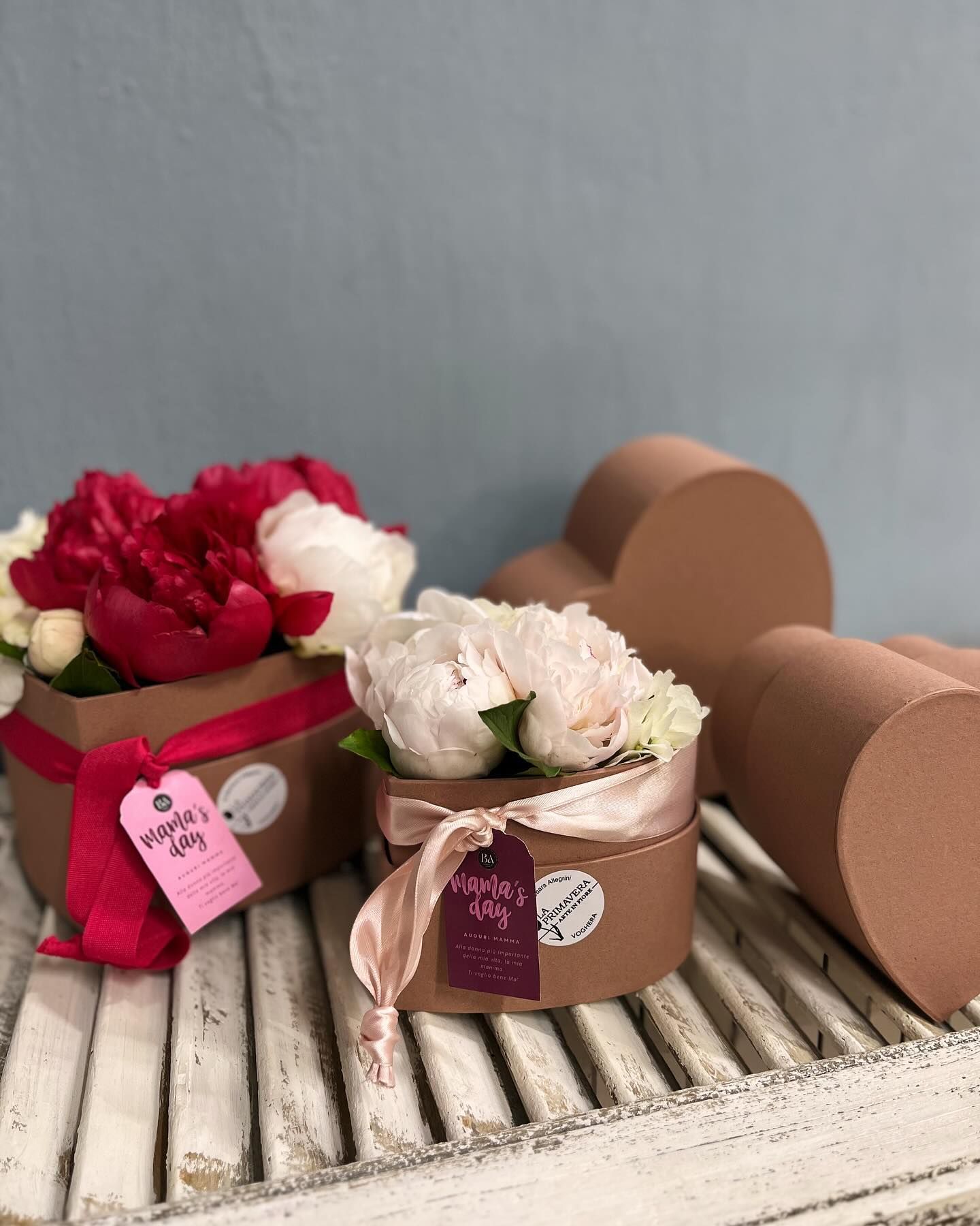 Tre scatole piene di fiori sono sedute su un tavolo di legno.