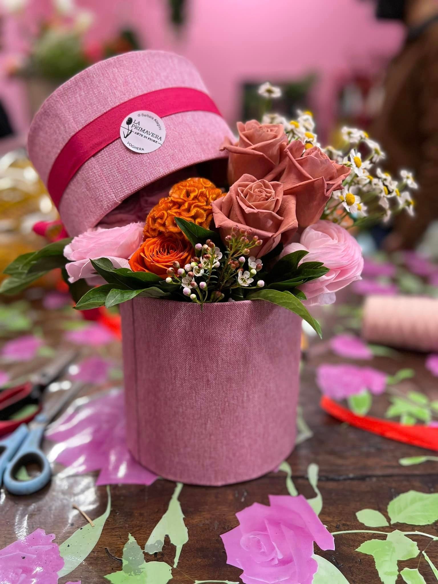 Su un tavolo è posata una scatola rosa piena di fiori