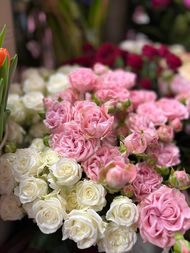 Un mazzo di rose rosa e bianche è seduto su un tavolo.