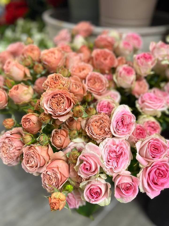 Un mazzo di rose rosa sedute una sopra l'altra su un tavolo.