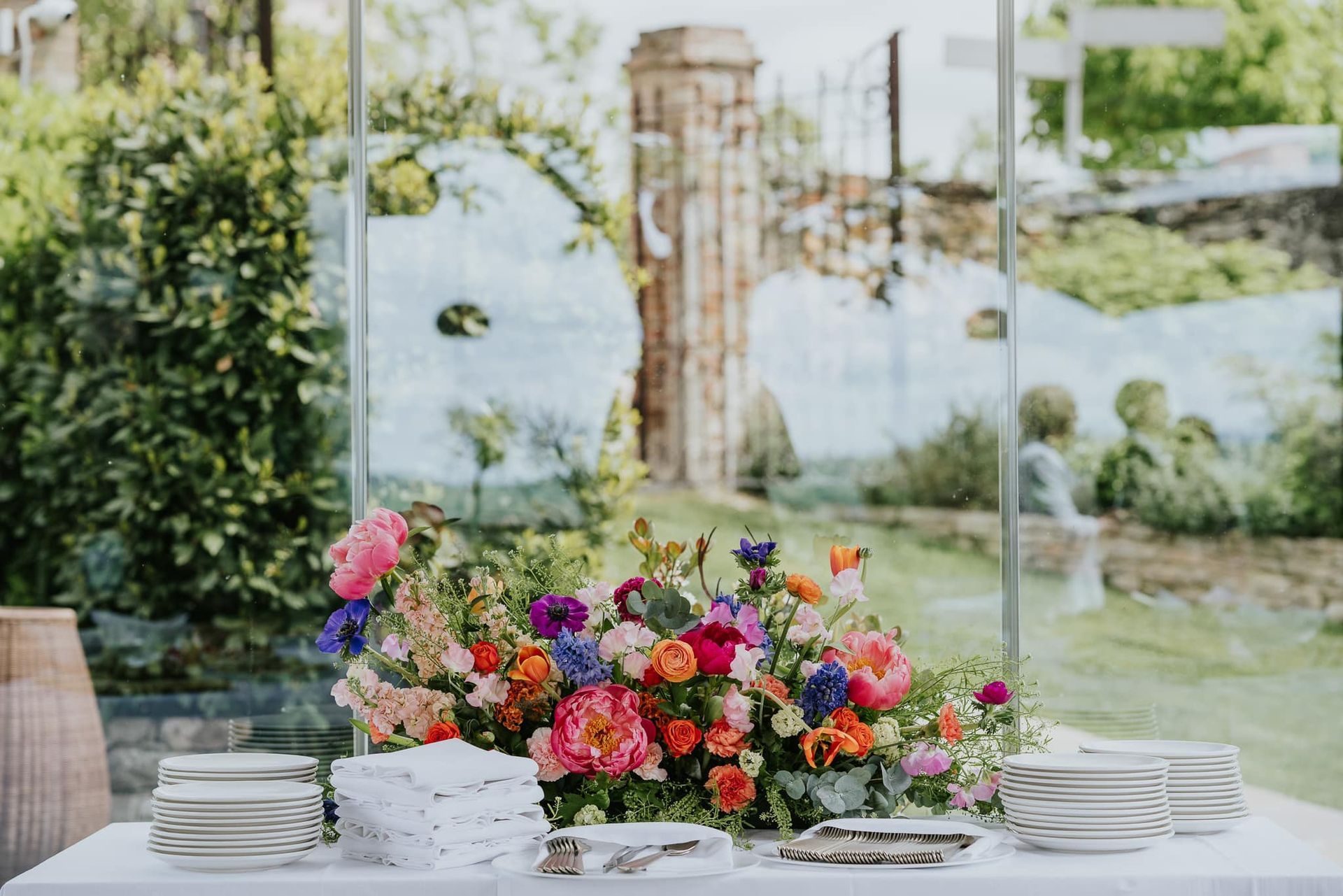 Un tavolo con piatti e fiori davanti a una parete di vetro.