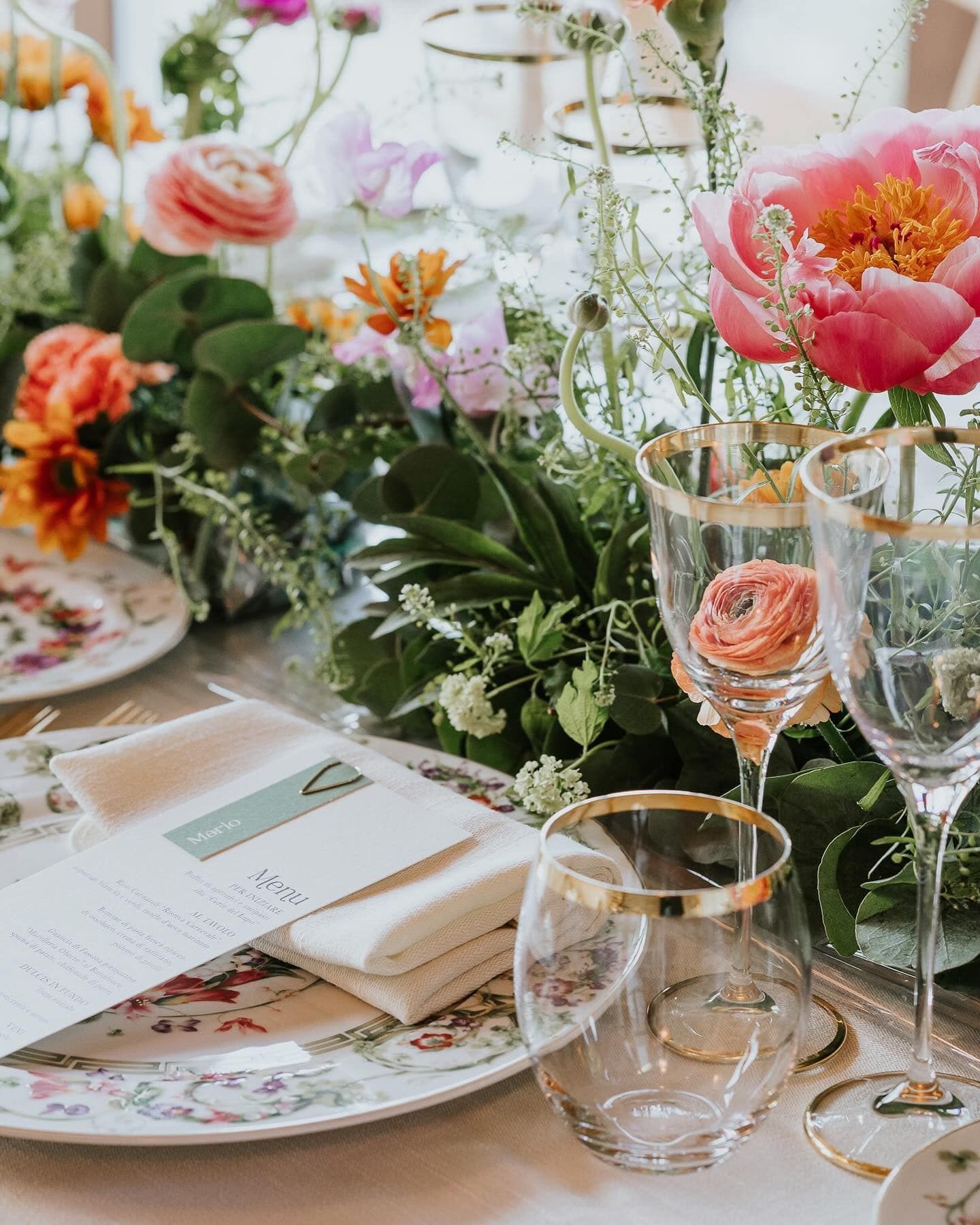 Un tavolo con sopra piatti, bicchieri e fiori.