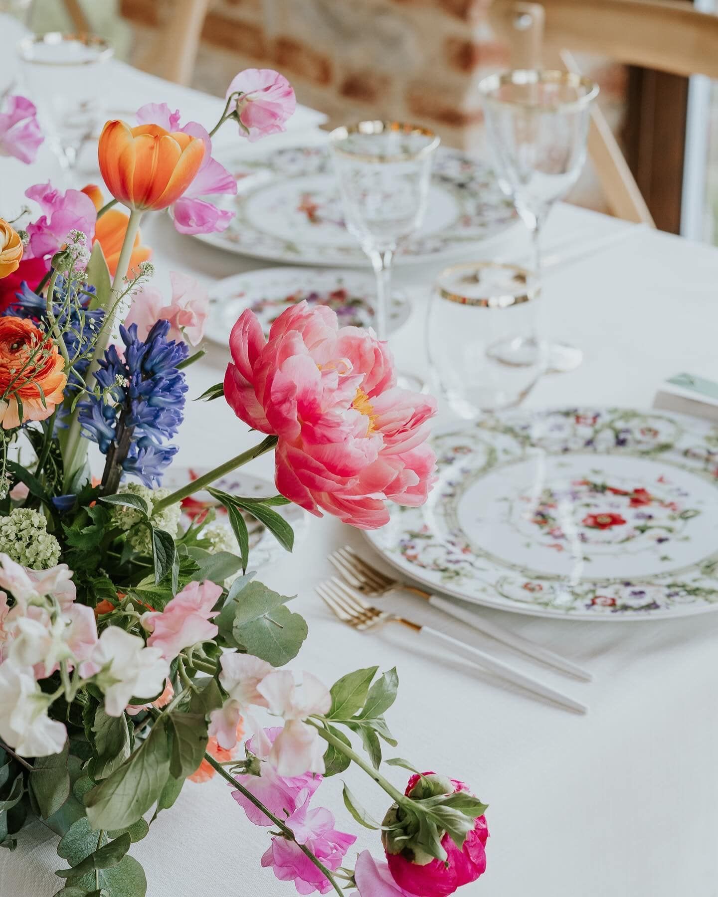 Un tavolo con sopra piatti, utensili e fiori.