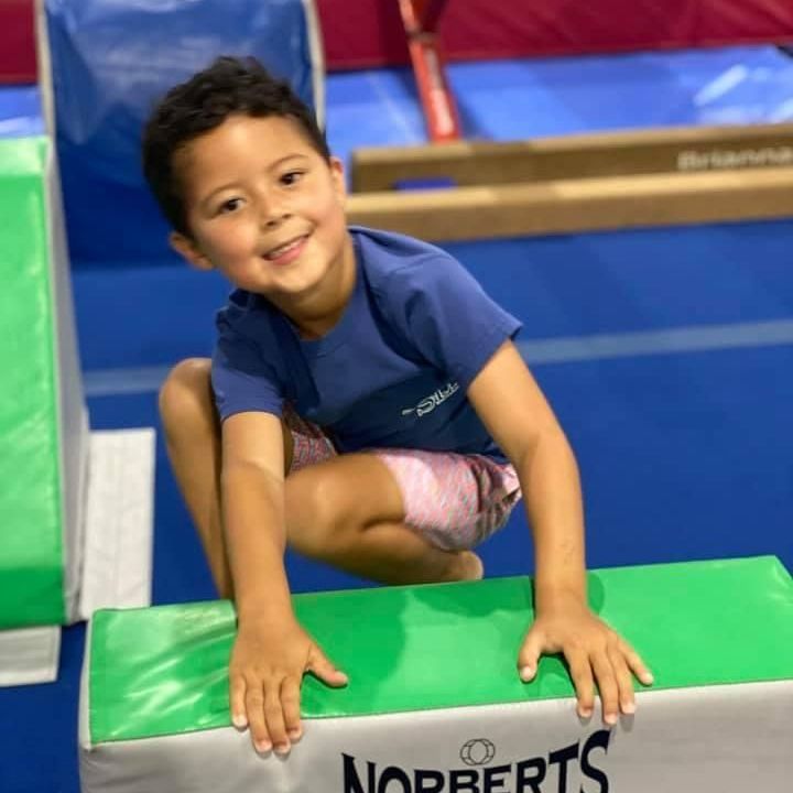 A young boy is squatting on a norberts mat