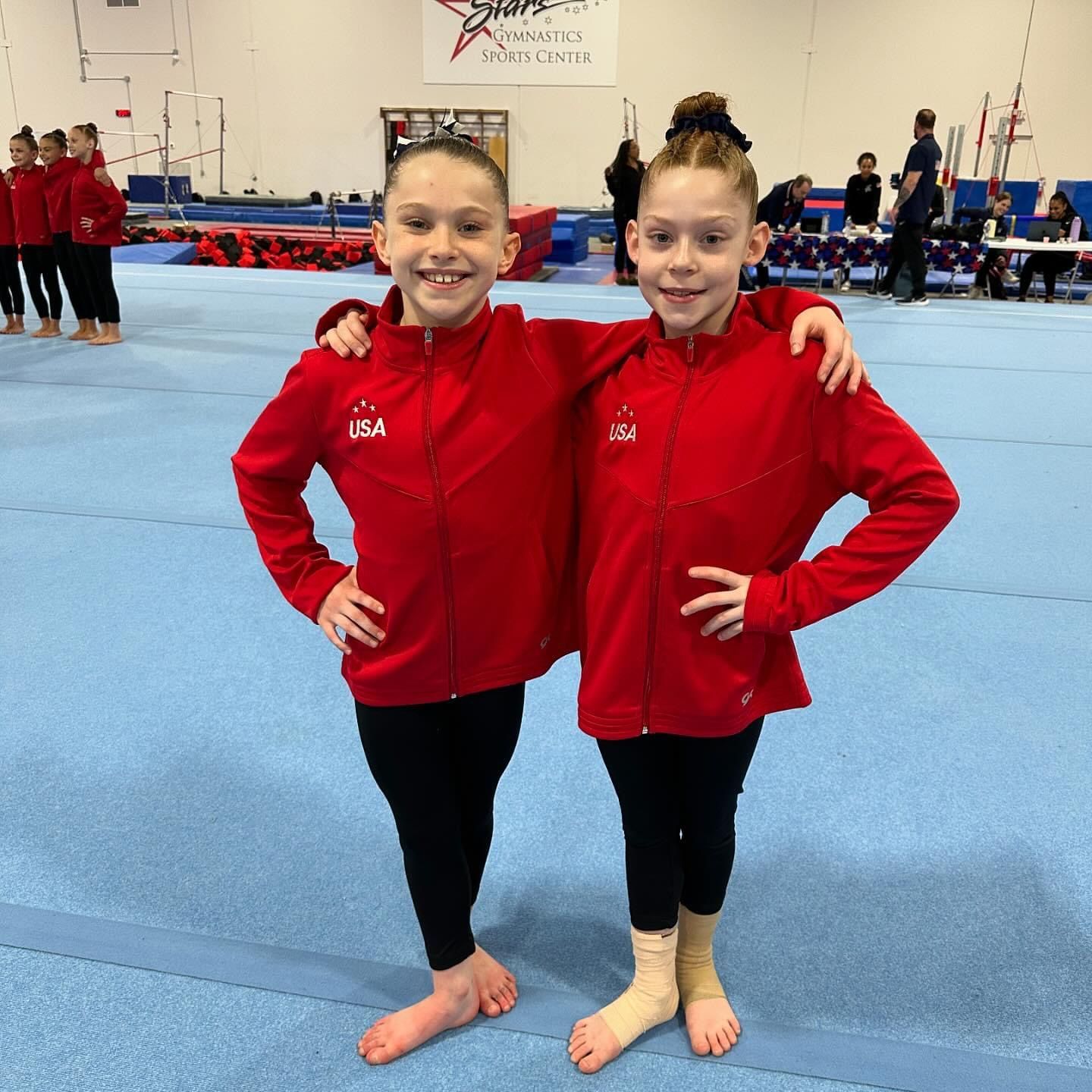 Two young girls wearing red jackets with the word usa on them