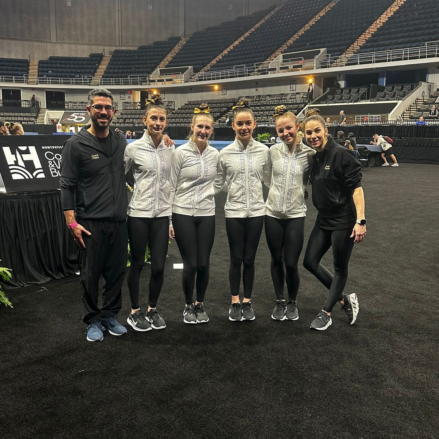 A group of young girls are posing for a picture with the word gymnastics in the background