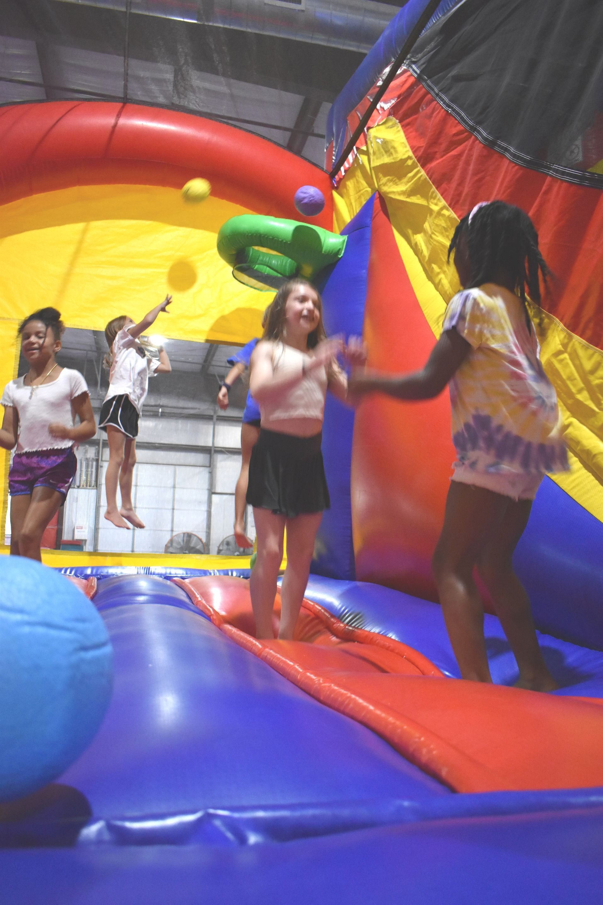 A group of young girls are playing on a bouncy house.