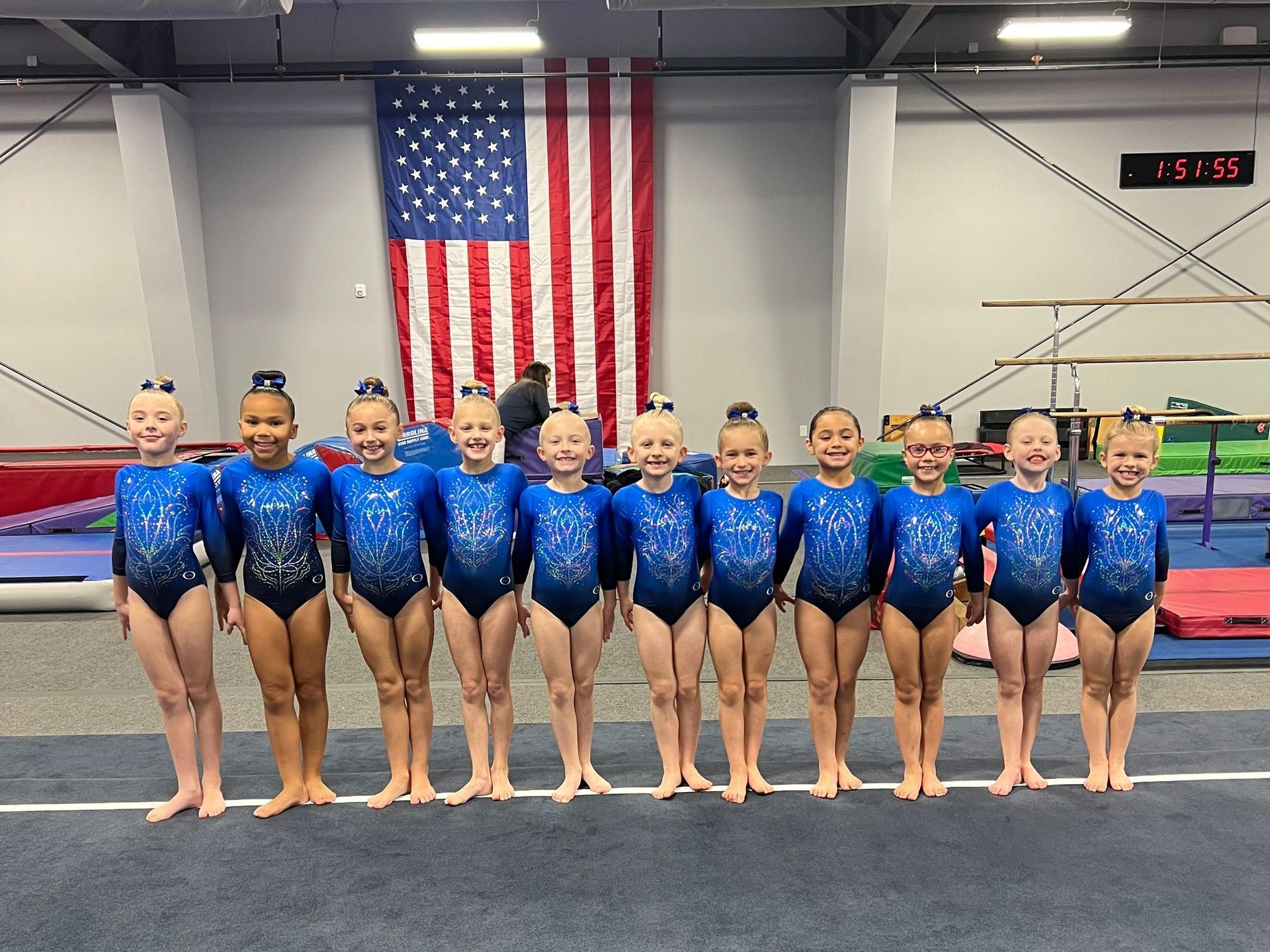 A group of young girls are posing for a picture in front of an american flag.