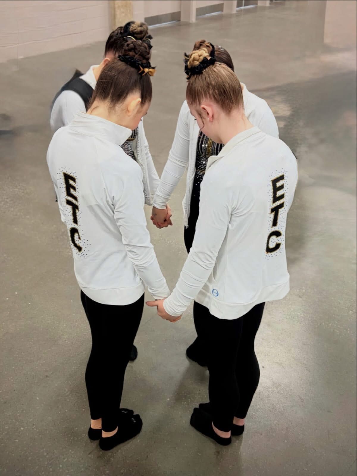 A group of young girls are posing for a picture with the word gymnastics in the background