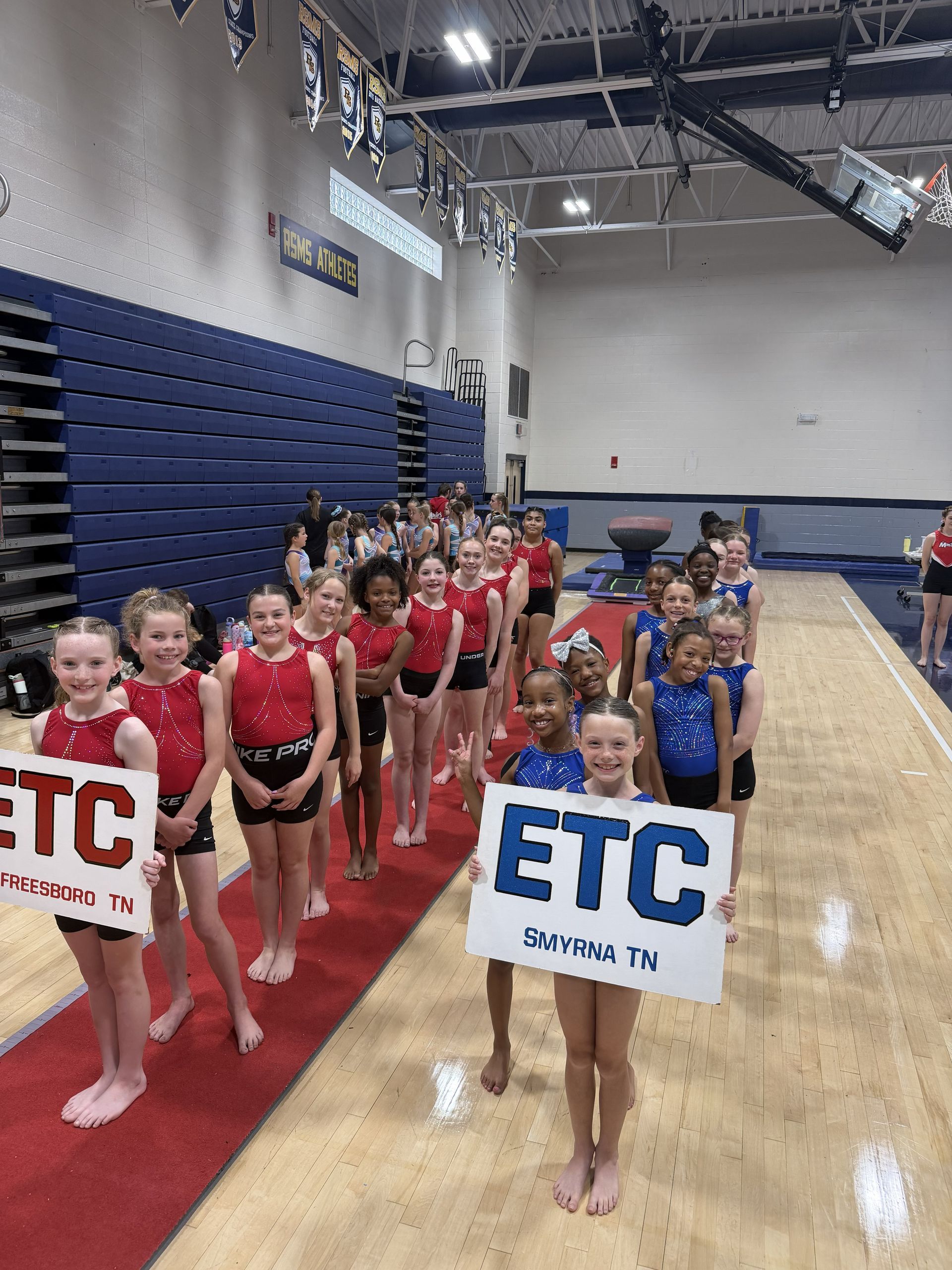 Three young girls are sitting on the floor holding medals.