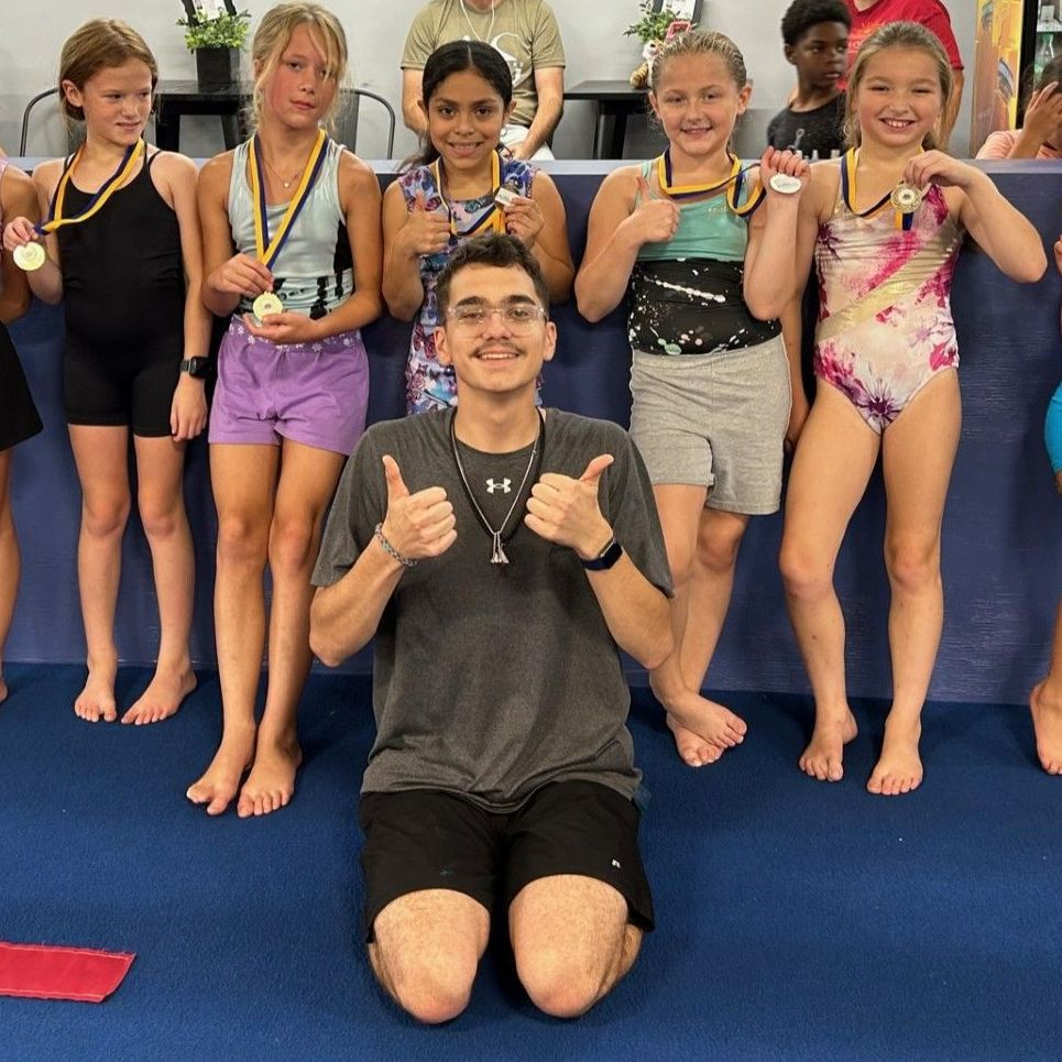 A group of young girls are posing for a picture with a man giving a thumbs up