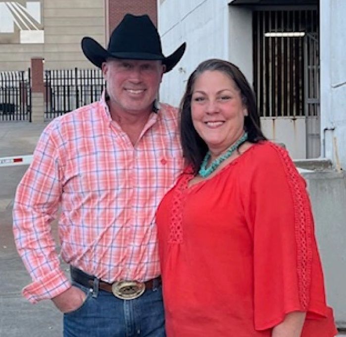 A man in a cowboy hat stands next to a woman in a red shirt