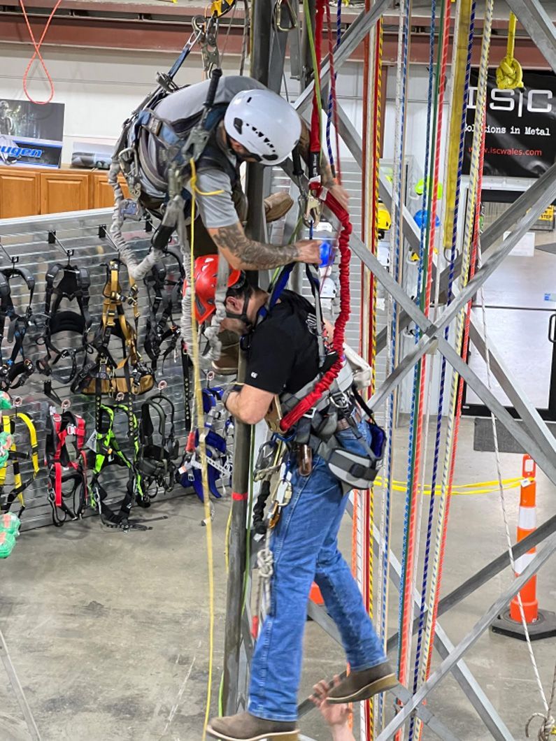 Two men are working on a pole in a building.