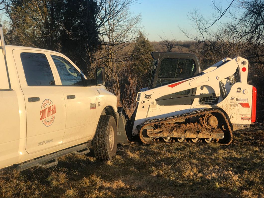 A white truck is parked next to a bulldozer in a field.