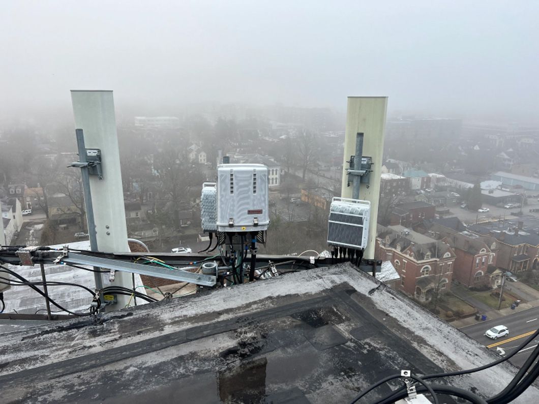 A rooftop with antennas on it and a city in the background.