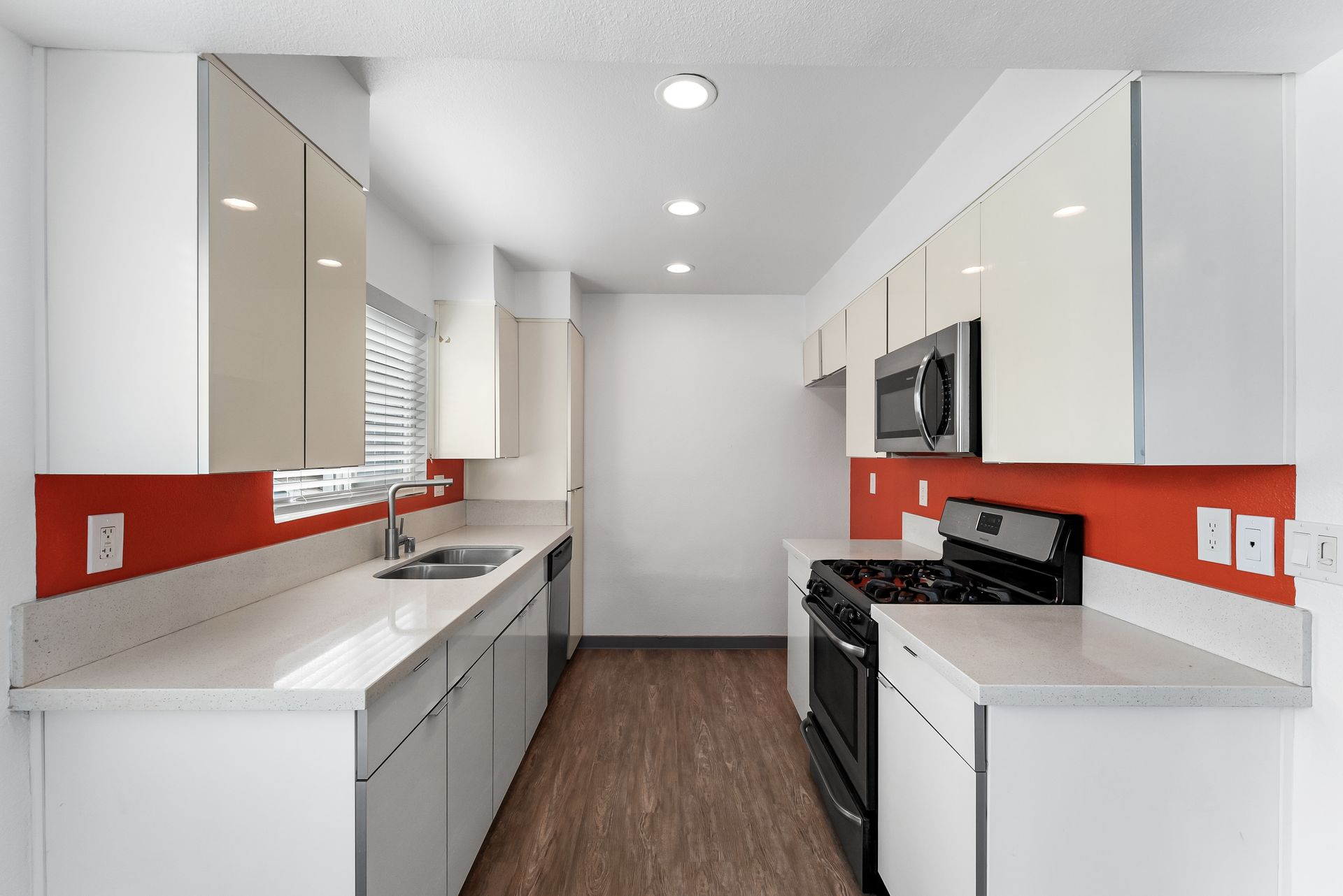 Sliding Photo Gallery Displaying Apartment Features- Kitchen with orange wall, white cabinets and counters, black stove