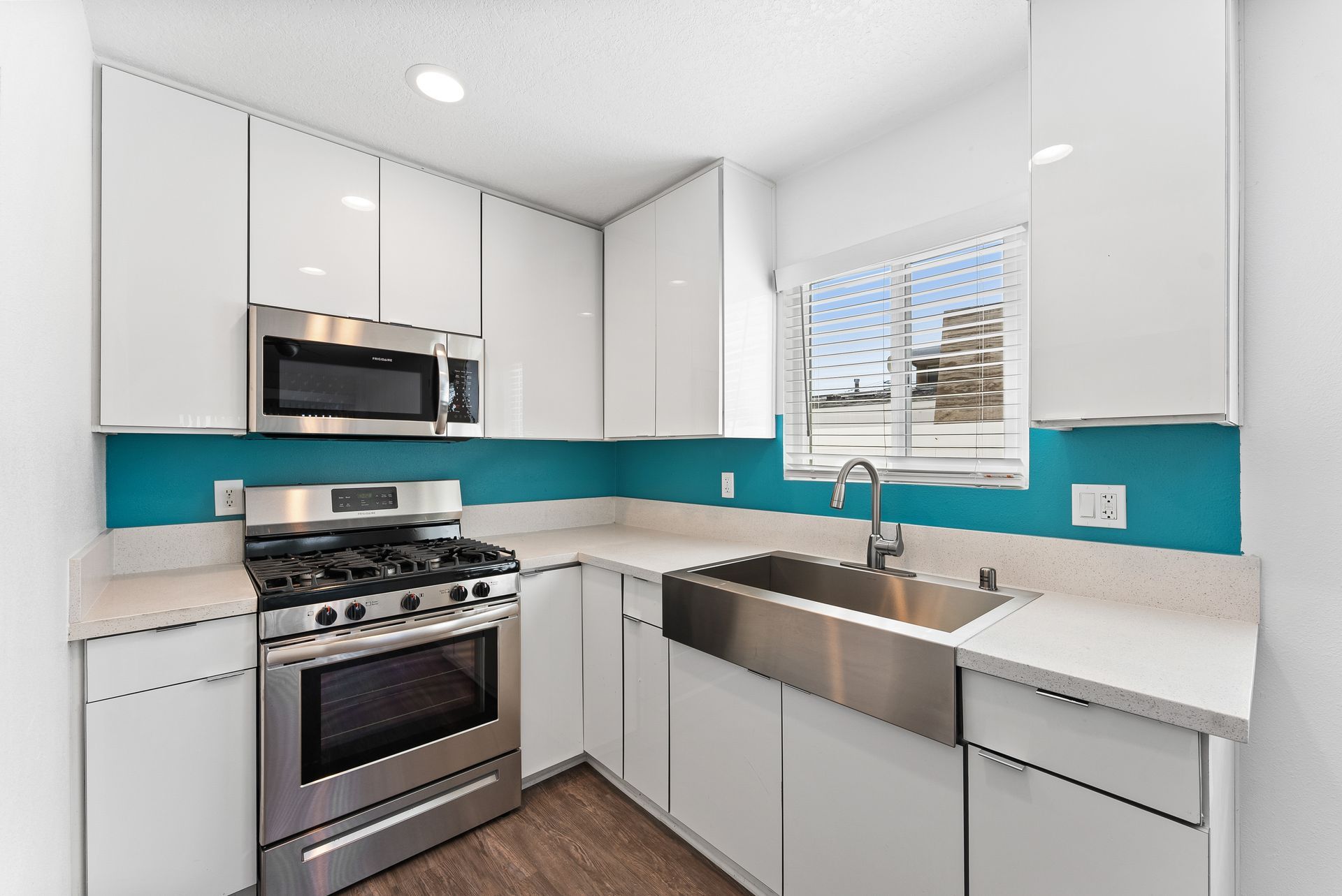 Sliding Photo Gallery Displaying Apartment Features- Kitchen with Blue Walls, white counters and cabinets, steel stove, and large steel sink
