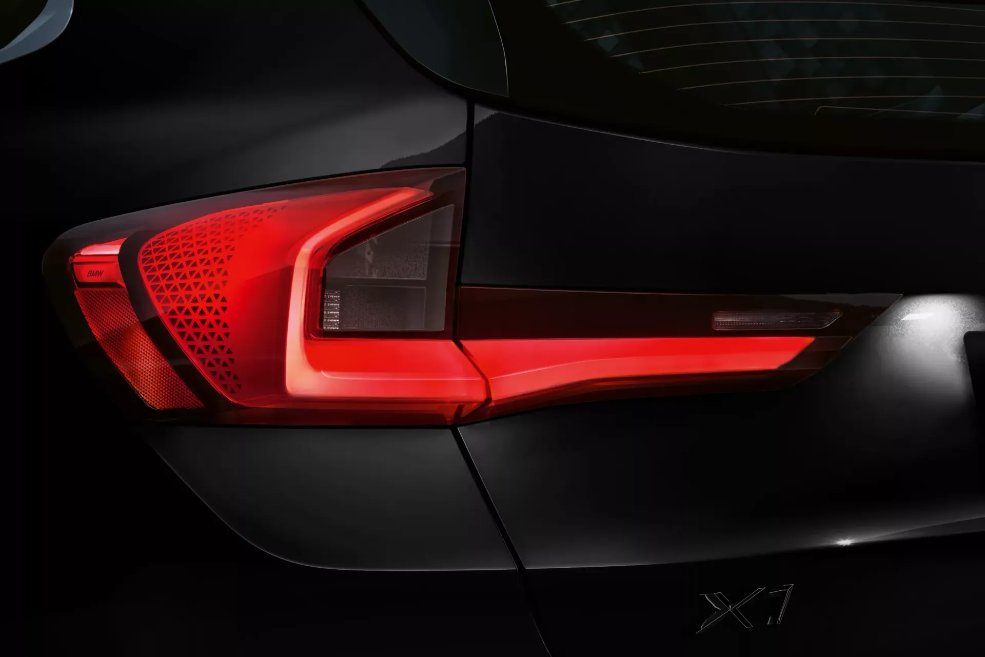 Taillight on a dark-colored SUV, emitting a red glow.