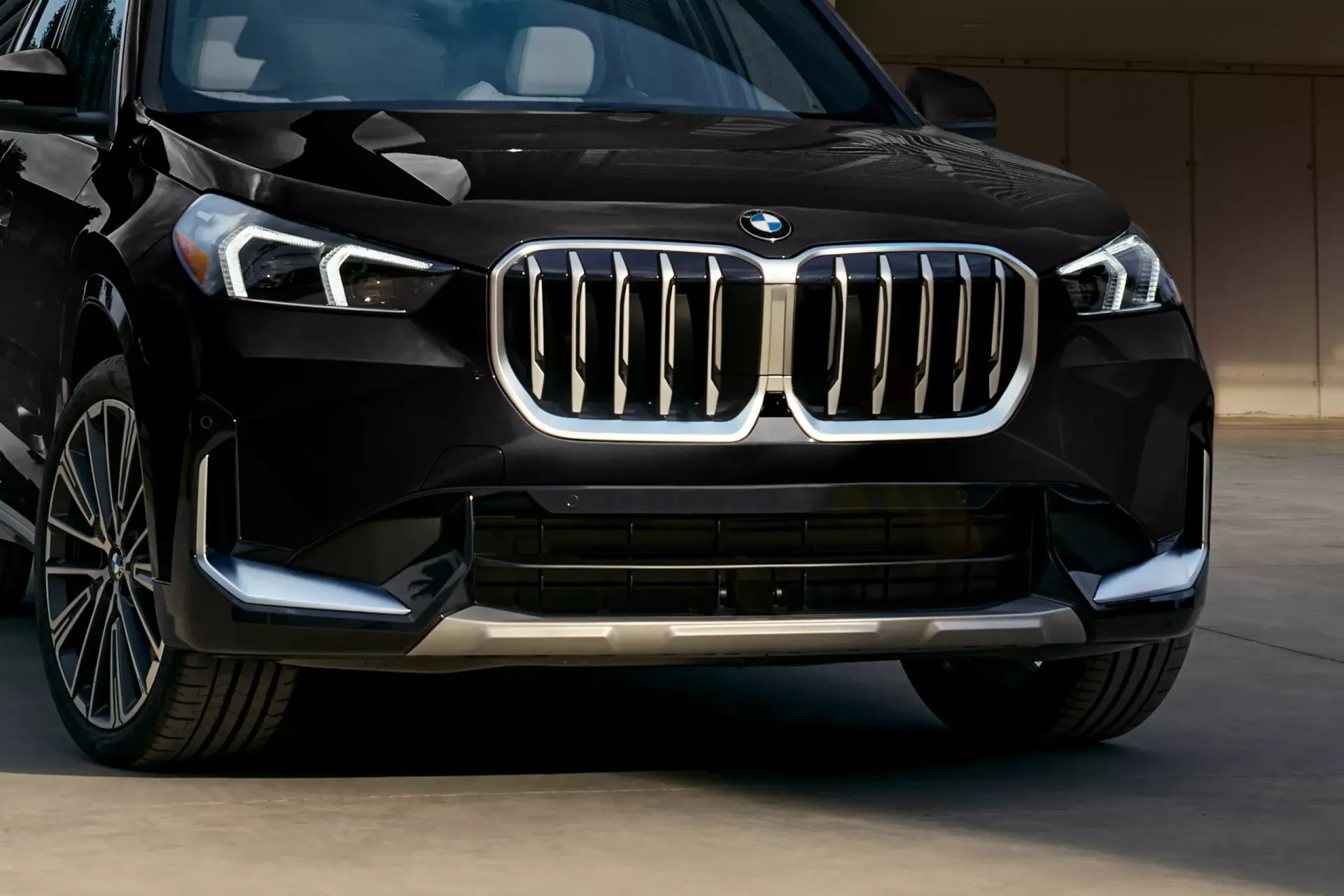 Black BMW SUV, front view, chrome grill, silver trim, parked outdoors.