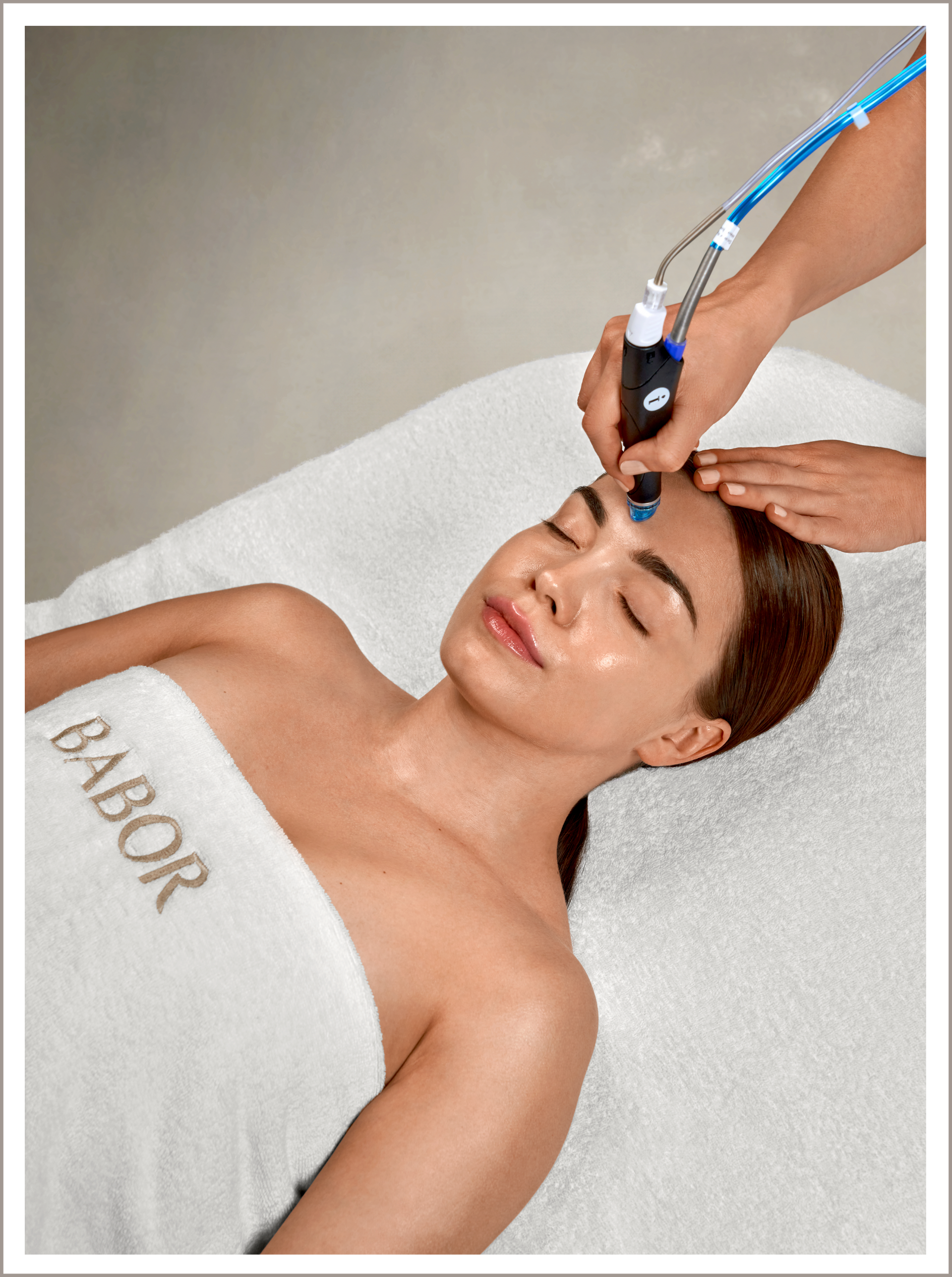 Eine Frau liegt auf einer Liege in einem Babor-Handtuch und lässt ihr Gesicht behandeln