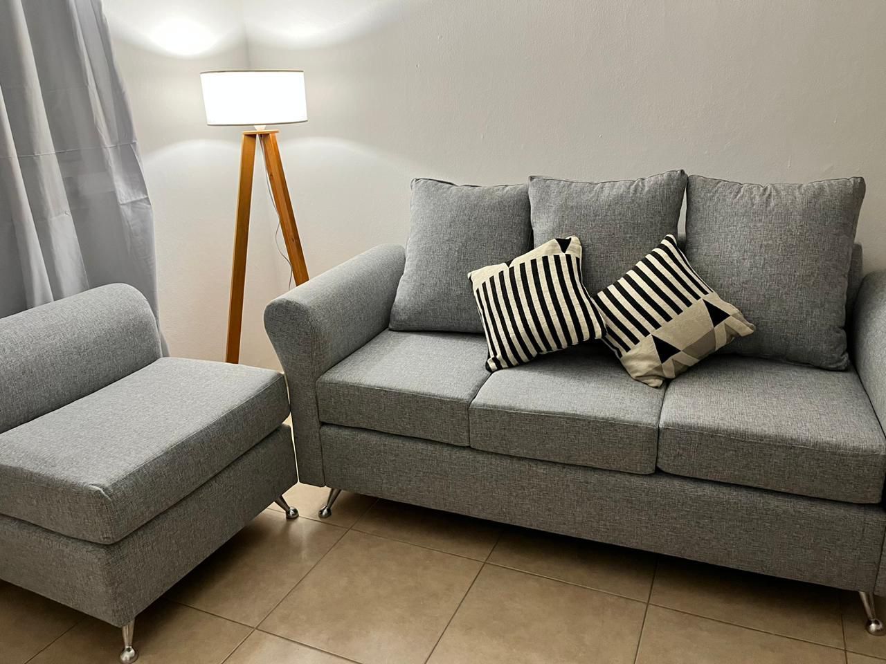 Una sala de estar con un sofá, una silla y una lámpara.