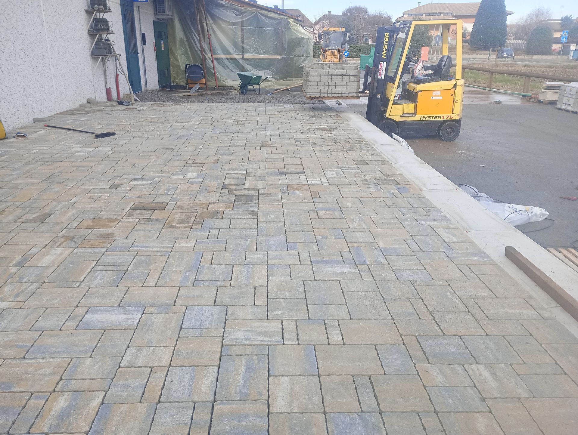 Un operatore di carrello elevatore sposta le pietre del selciato su un patio appena pavimentato, in un cantiere edile.