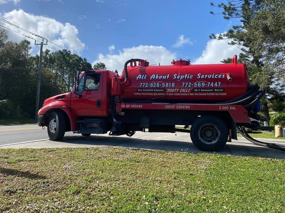 Red septic service truck on a road. 