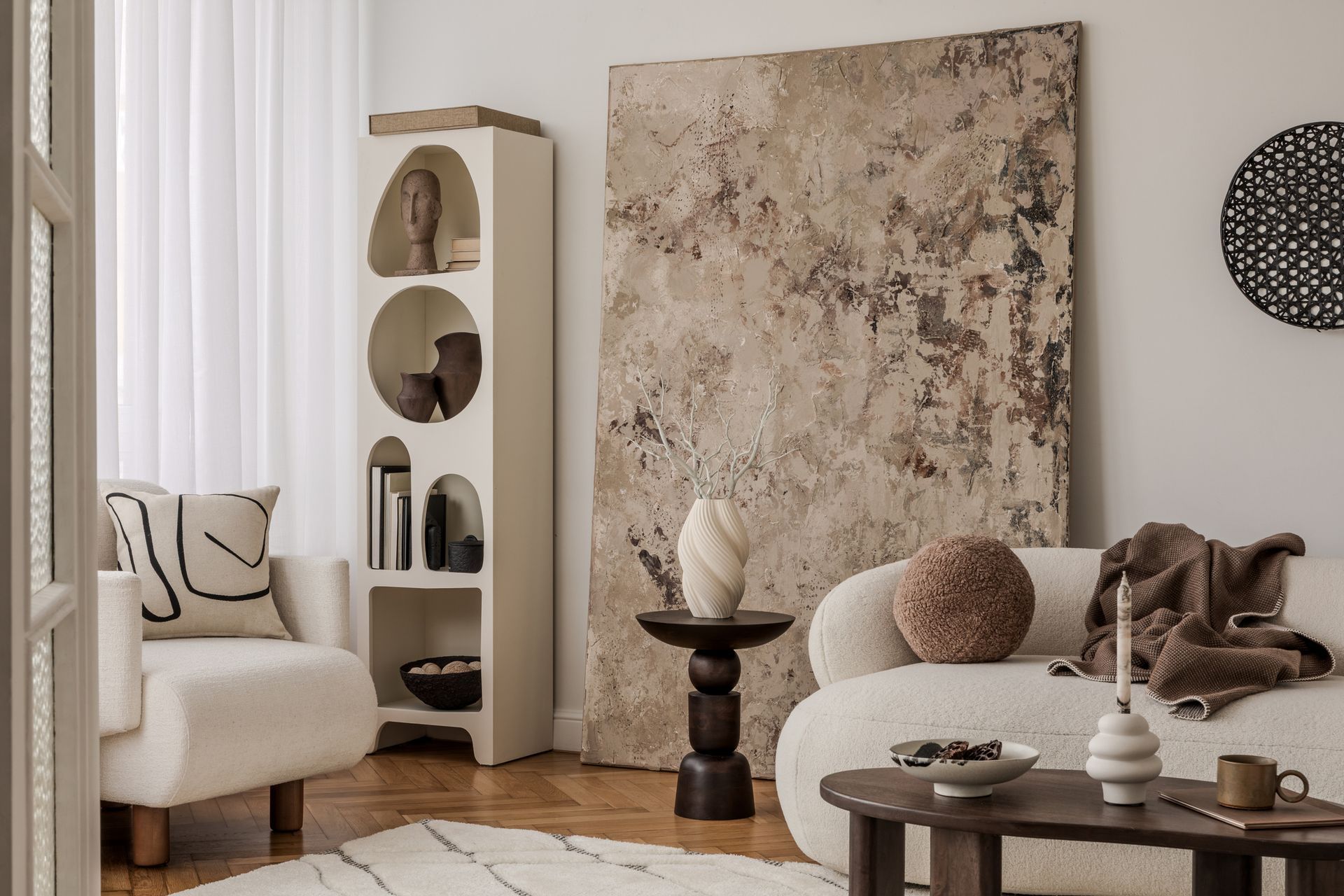 Cozy living room with a white couch, wooden furniture, and large abstract artwork.