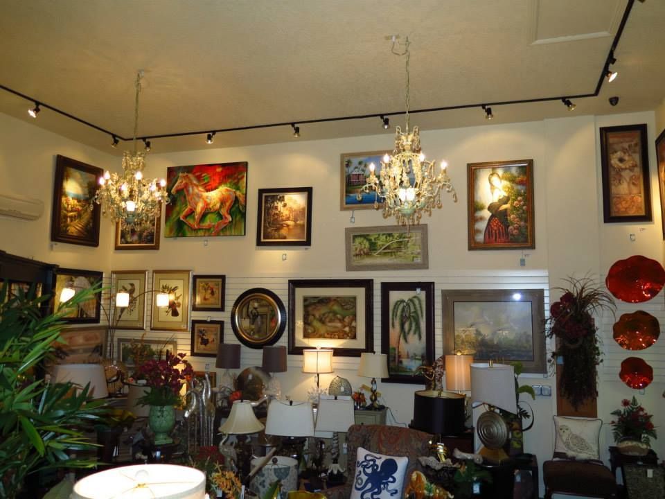 Art gallery interior with paintings, chandeliers, and lamps on display.