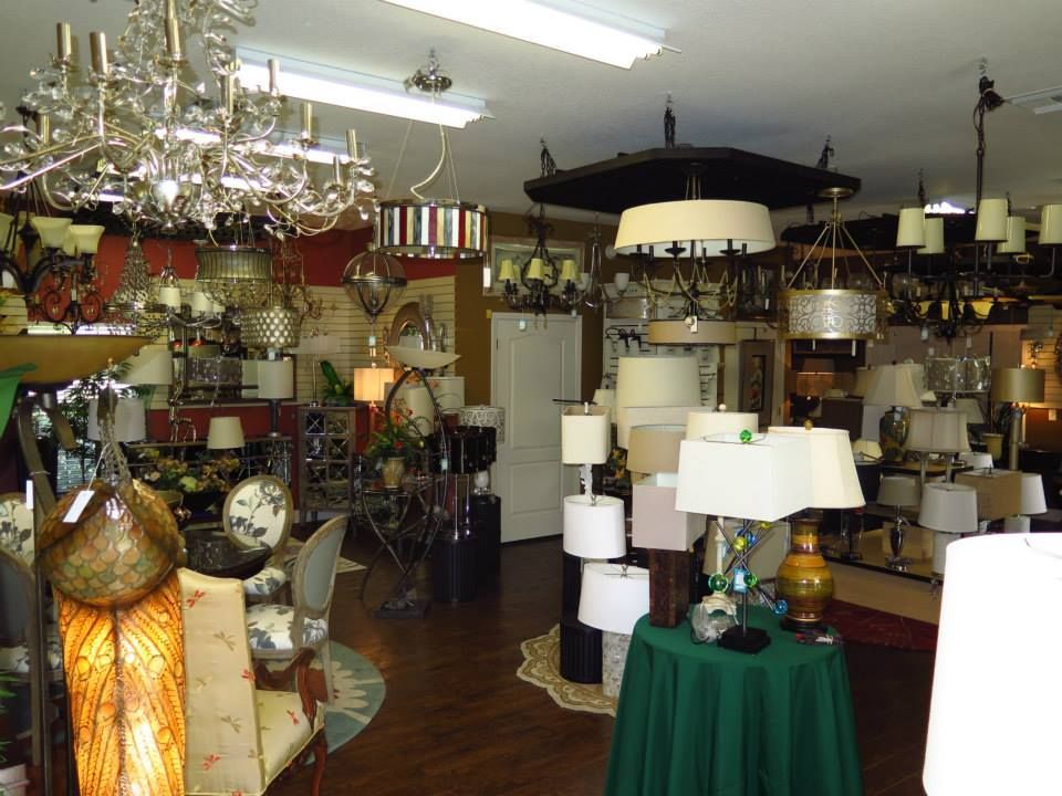 Interior of a lighting store with many lamps and chandeliers on display, including a table with a green cloth.
