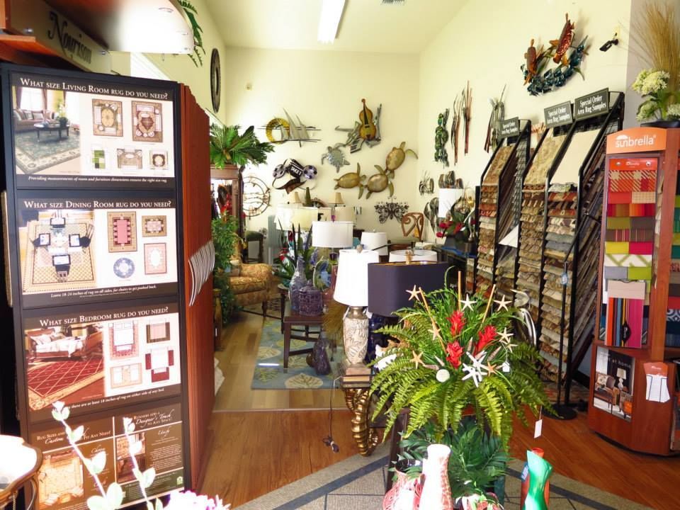 Interior of a home decor store; rugs, wall art, and samples displayed.