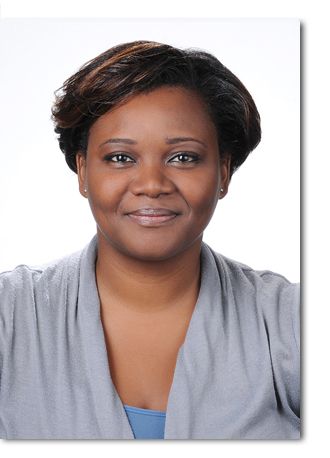 A woman in a grey sweater is smiling for the camera