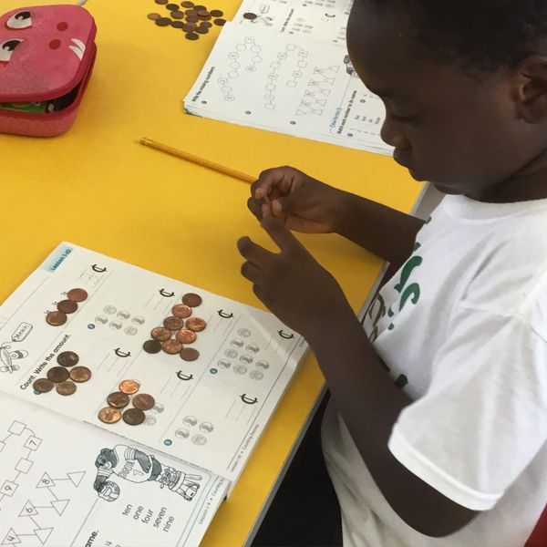 A young boy is sitting at a table counting coins