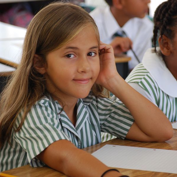 A girl in a green and white striped shirt sits at a desk