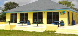 A yellow building with blue trim and tables in front of it.