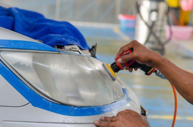 A person is polishing the headlight of a car.