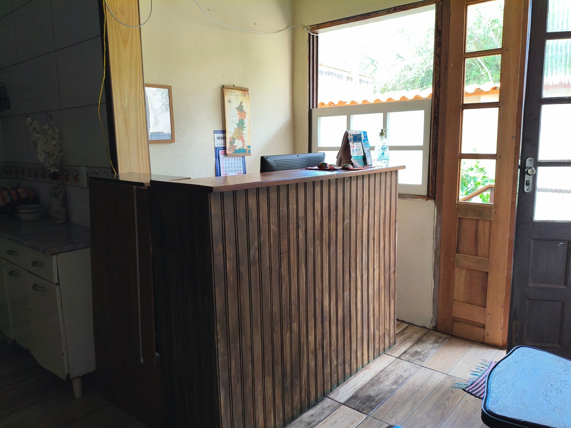 Balcão de recepção de madeira em uma sala com janela e porta.