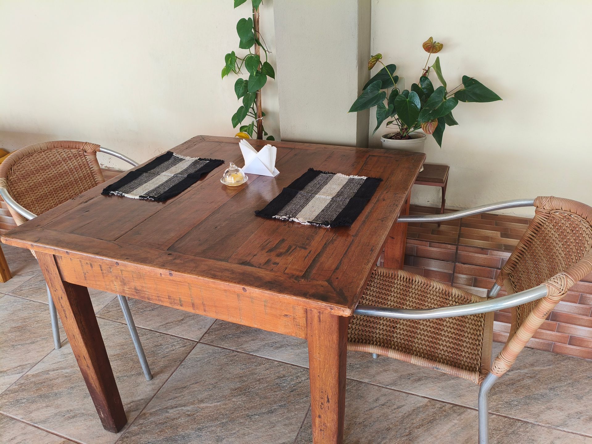 Uma entrada convidativa com duas cadeiras, uma prateleira com plantas e vista para um corredor.