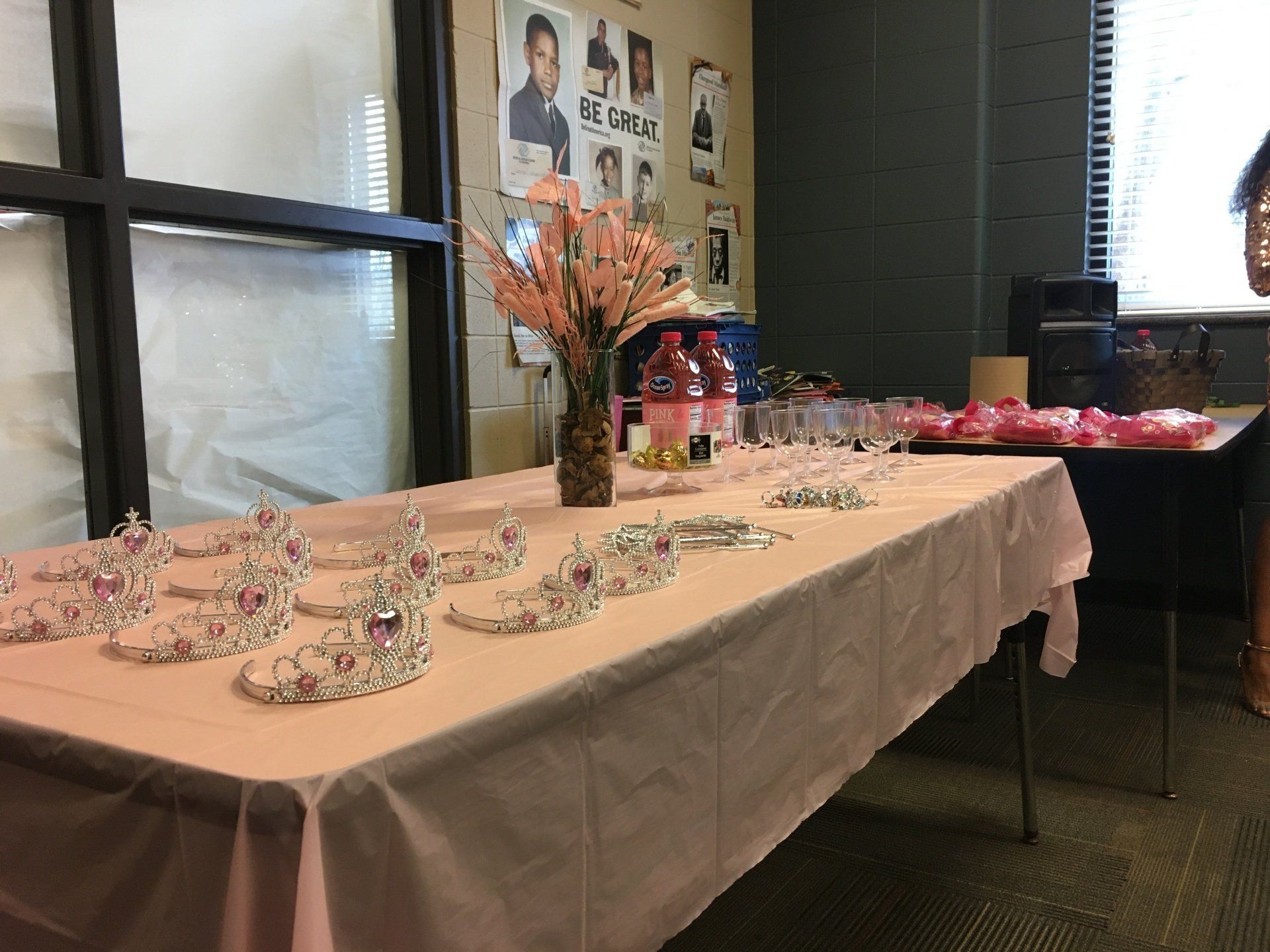 Table set with crowns, pink flowers, drinks, and snacks, likely for a celebration.