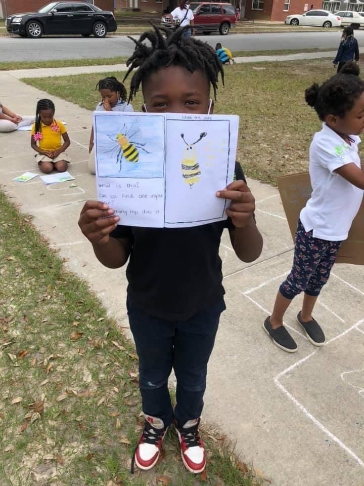Child holding paper drawing of a bee at Boys & Girls Club