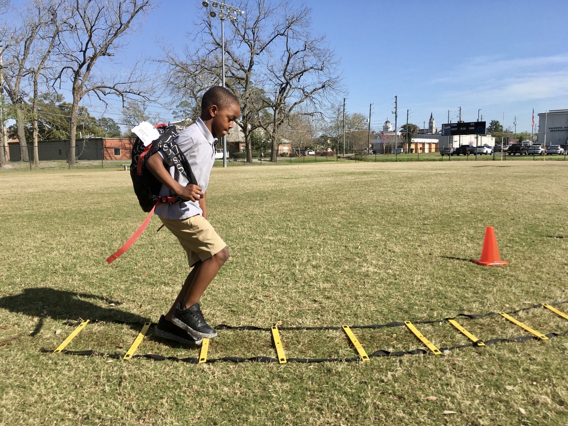 Boy running across ladder exercise at Boys & Girls Club field
