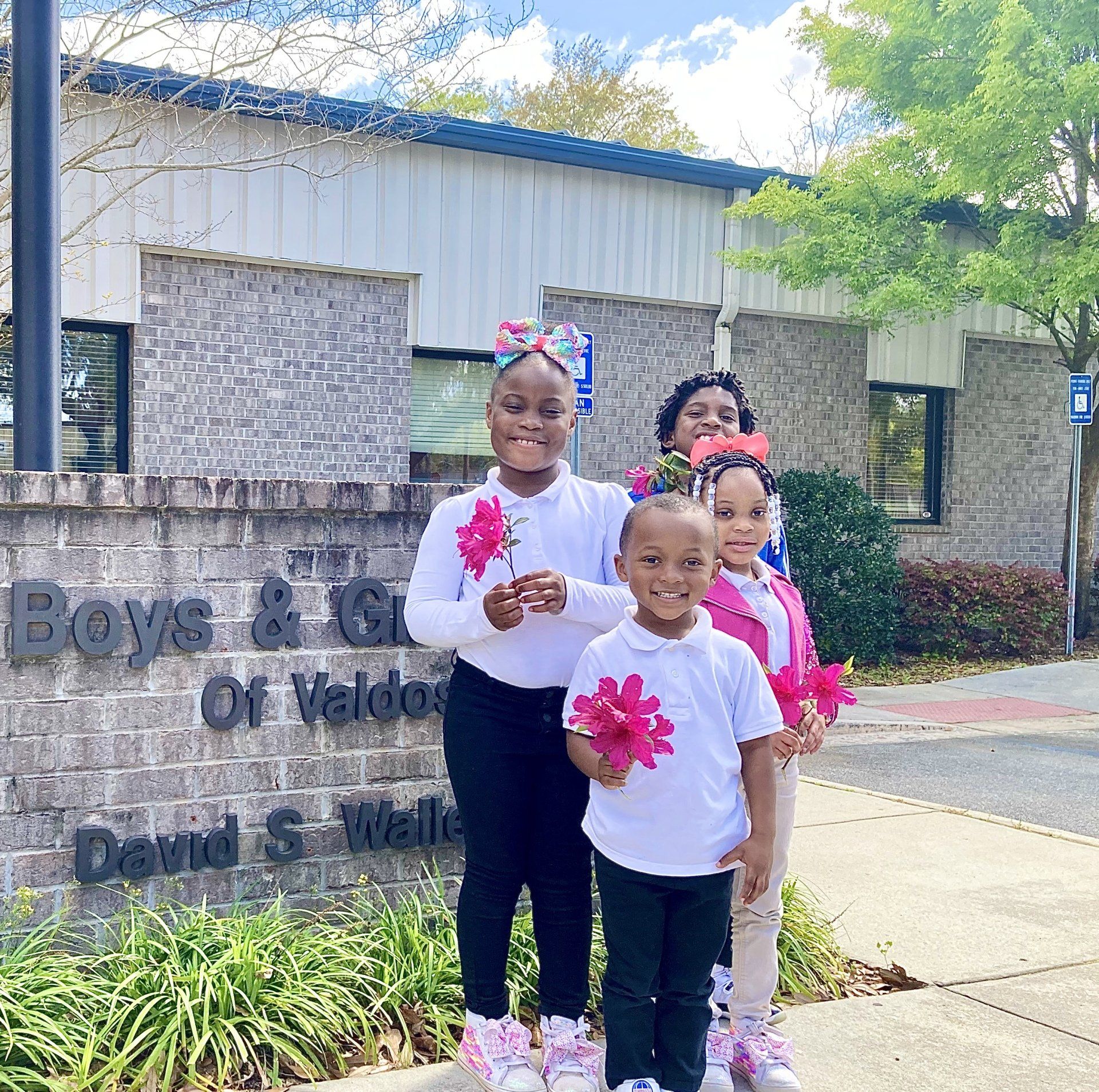 Three kids smiling outside Boys & Girls Club building