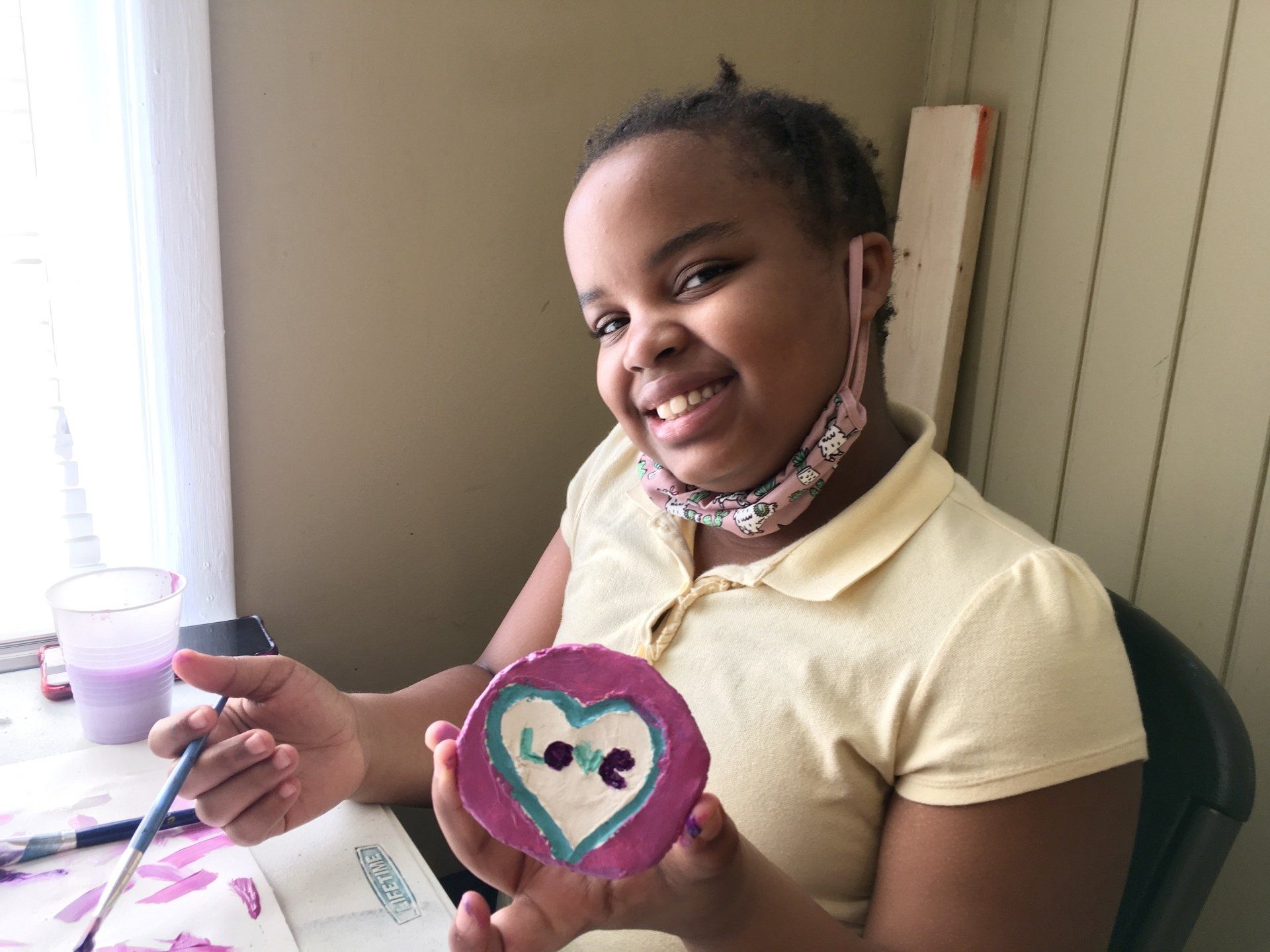 Girl smiling and holding painted artwork at Boys & Girls Club