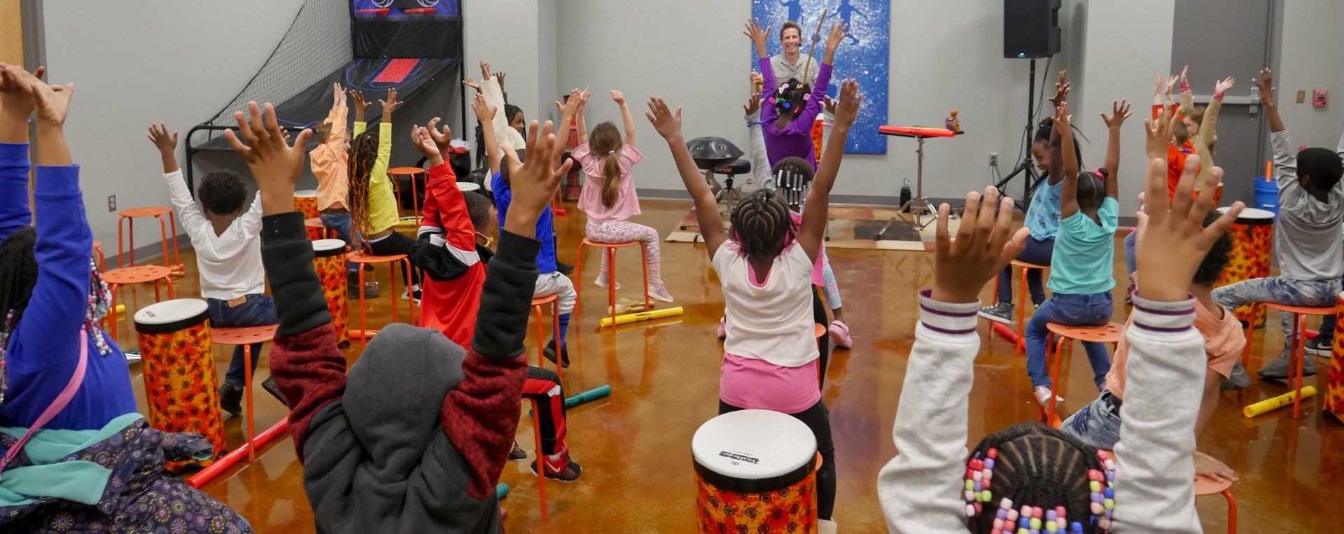 Kids raising hands during interactive drumming activity at Boys & Girls Club