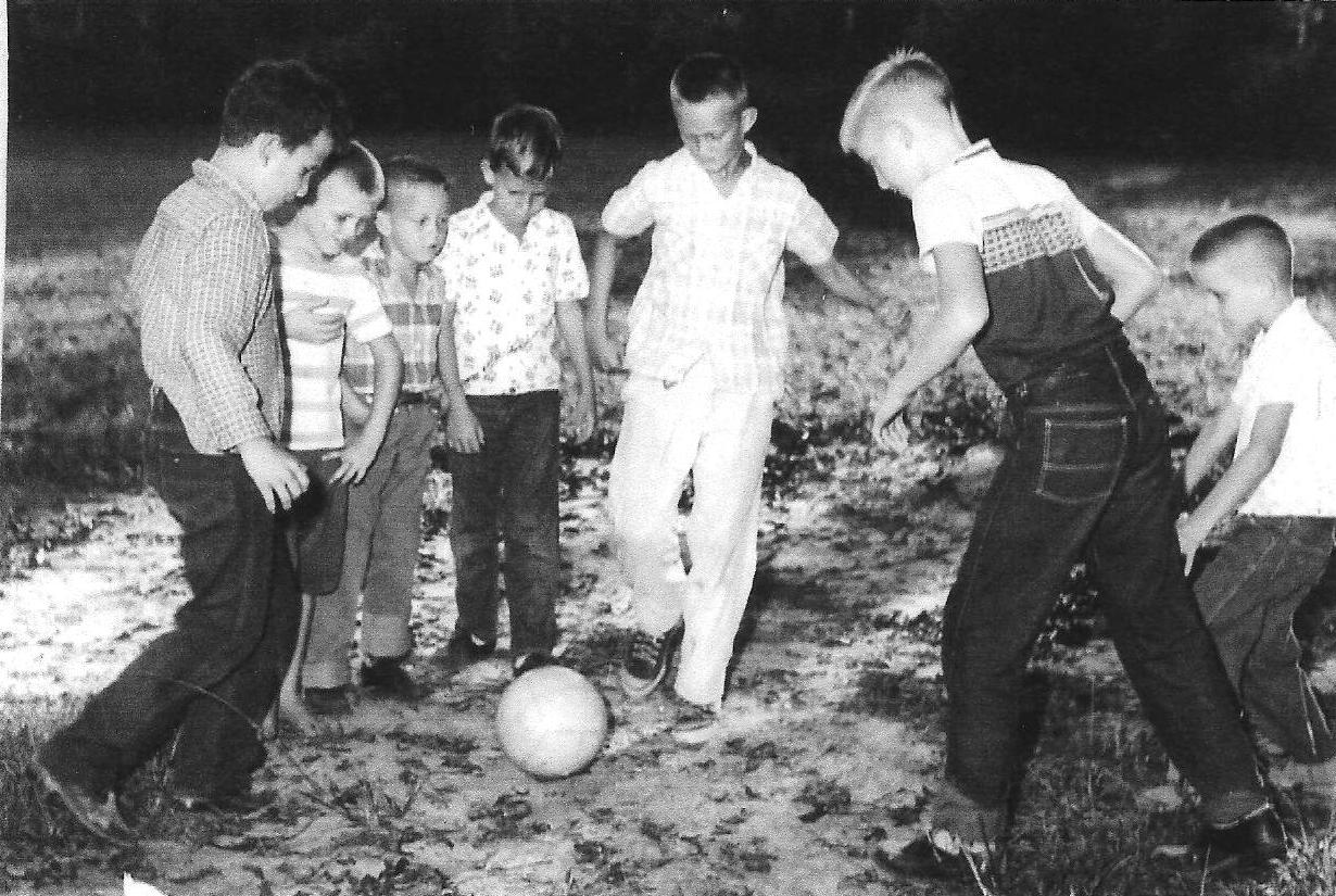 Black-and-white 1950s photo of kids playing soccer together